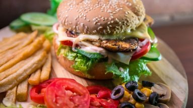 hamburger with vegetables and meat beside French fries