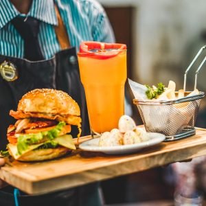 person serving burger with pitcher of juice